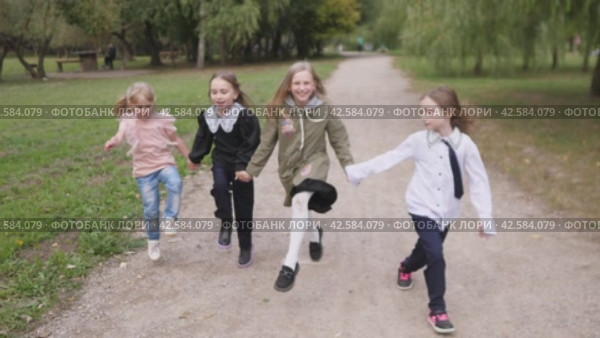 A group of happy children are running happily through the park holding hands and rejoicing and laughing. Стоковое видео, видеограф Громов Александр / Фотобанк Лори