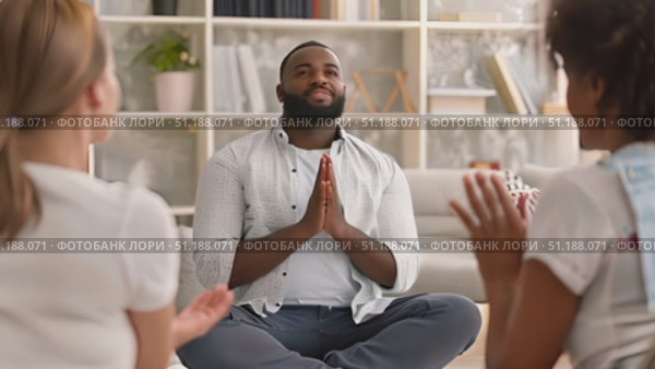 A group sits in a well-lit living room, with one leader guiding a meditation session focused on relaxation and mindfulness. Стоковое AI-видео, аниматор Данила Большаков / Фотобанк Лори