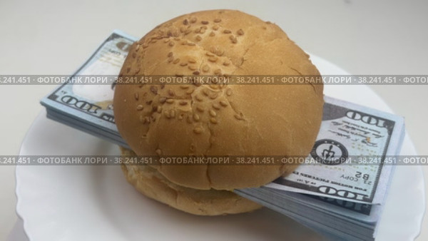A hamburger with a wad of dollars is spinning on a white plate. Food and money. Стоковое видео, видеограф Ярославский Максим / Фотобанк Лори
