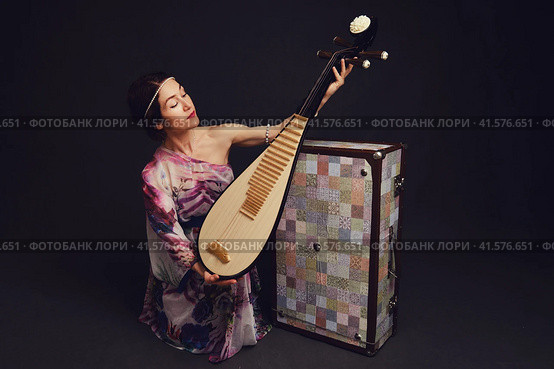 A happy female musician in Asian clothes on a studio black background. A smiling woman with a stringed musical instrument from Asia on a dark background. Стоковое фото, фотограф Андрей Журавлев / Фотобанк Лори