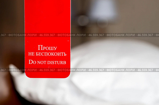 A hotel room with a red sign that says "Please do not disturb." The concept of a hotel stay. Стоковое фото, фотограф Photojuli / Фотобанк Лори