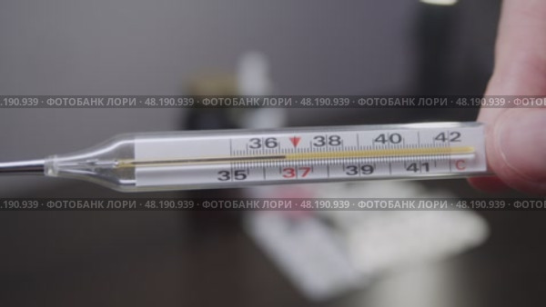 A human hand holds a thermometer, with a mercury column indicating the normal body temperature in degrees Celsius. Стоковое видео, видеограф Strunov David / Фотобанк Лори