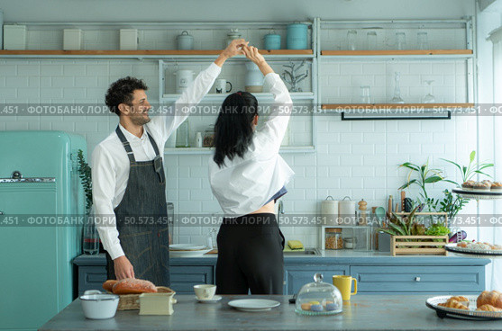 A husband wears an apron while cooking dinner with his wife. He was dancing happily before entering the kitchen to cook. Стоковое фото, агентство Ingram Publishing / Фотобанк Лори