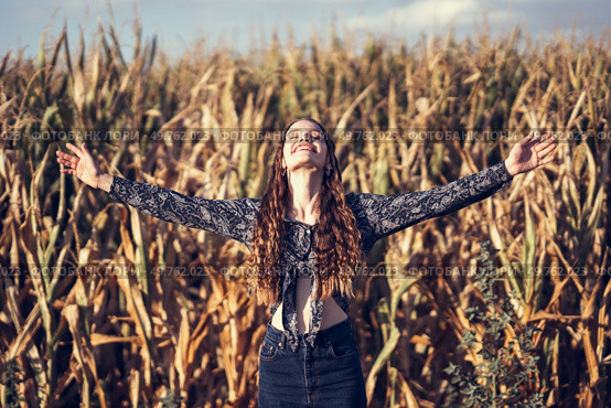 A joyful woman stands gracefully in a vast cornfield, her arms wide open and outstretched, celebrating the beauty of nature and the sense of freedom that comes with it under a clear, bright blue sky. Energizing Freedom in Nature A Woman Fully Embracing the Beautiful Outdoors Around Her. Стоковое фото, агентство Ingram Publishing / Фотобанк Лори