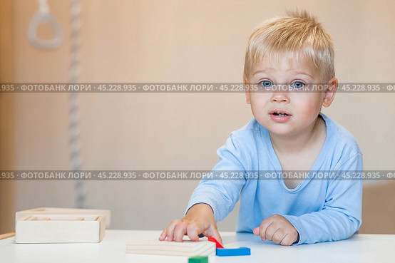 A little boy of 2 years old is playing a developing logistics constructor. Children's wooden toys. Montessori for child development. Стоковое фото, фотограф Photojuli / Фотобанк Лори