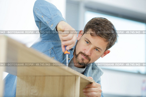 a male carpenter tightening screws. Стоковое фото, агентство Ingram Publishing / Фотобанк Лори