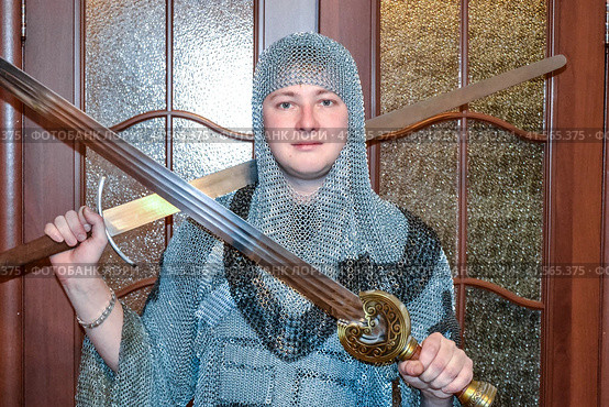 A man dressed up in a knight's hauberk at home in his room. Knight's sword in the hands of a man. Стоковое фото, фотограф Леонид Еремейчук / Фотобанк Лори