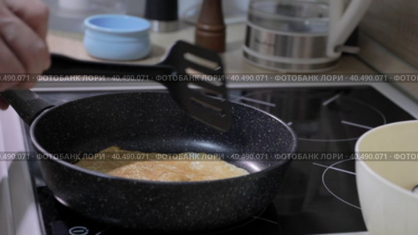 A man flips a pancake with a spatula in a pan. Стоковое видео, видеограф Юрий Поздников / Фотобанк Лори