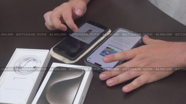 A man is transferring data from the old iPhone 7 Plus to the new iPhone 15 Pro Max. Редакционное видео, видеограф Vadzim Yakubovich / Фотобанк Лори