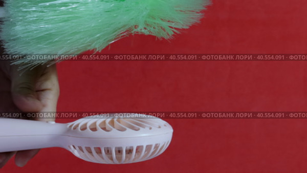 A man presses the power button on a portable portable fan. Shows operating modes. The fan blows on the brush, demonstrating the strength of the air flow. The brush falls. On a coral background. Стоковое видео, видеограф Vadzim Yakubovich / Фотобанк Лори
