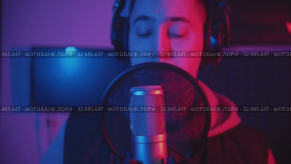 A man rapping through the pop-filter in the microphone - recording his track in the studio. Стоковое видео, видеограф Константин Шишкин / Фотобанк Лори