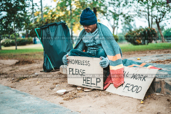 a man sitting beggars with homeless please help message. Selective focus. Стоковое фото, агентство Ingram Publishing / Фотобанк Лори