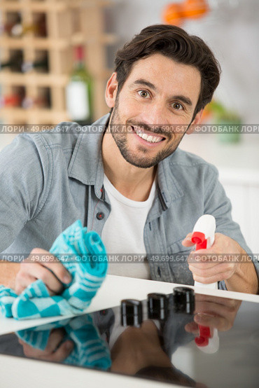 a man spraying detergent to clean the kitchen worktop. Стоковое фото, агентство Ingram Publishing / Фотобанк Лори