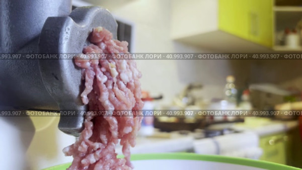A meat grinder for chopping fresh raw meat works against the background of the kitchen.  Focus on a working meat grinder. Стоковое видео, видеограф Ярославский Максим / Фотобанк Лори