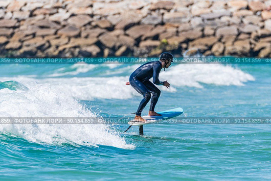 A middle aged man doing some foil surfing or hydrofoil surfing in the sea on a bright sunny day. Стоковое фото, агентство Ingram Publishing / Фотобанк Лори