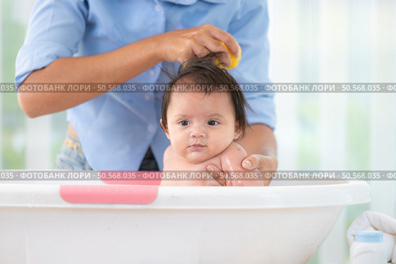 A mother bathes her little daughter in a small children’s tub. Стоковое фото, агентство Ingram Publishing / Фотобанк Лори