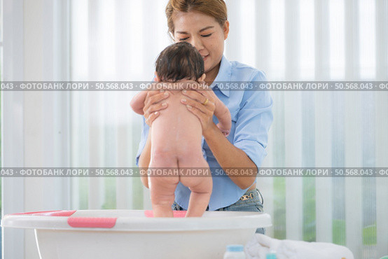 A mother bathes her little daughter in a small children’s tub. Стоковое фото, агентство Ingram Publishing / Фотобанк Лори