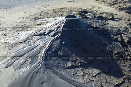 A mud volcano and a stream of grey clay from an eruption and gas escape. Cracked soil surface. Texture of a mudflow. Стоковое фото, фотограф Наталия Кирсанова / Фотобанк Лори