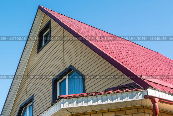A newly built two-storey house with a metal roof.  The roof is made of metal tiles. Protection of the house from atmospheric precipitation. Стоковое фото, фотограф Эдуард Белкин / Фотобанк Лори
