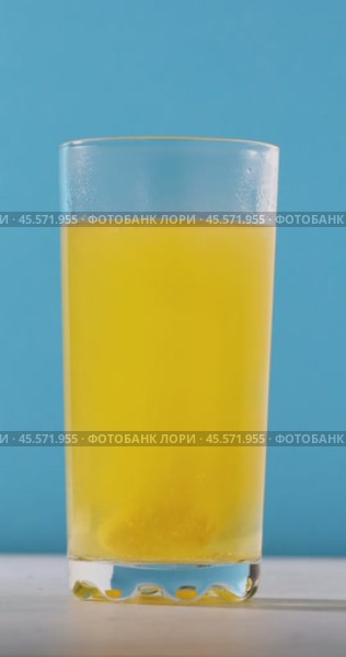 A person drops an orange-flavored quick-dissolving aspirin tablet into a glass of water. Стоковое видео, видеограф Сергей Чайко / Фотобанк Лори