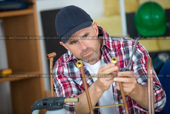 a plumber inspecting copper rod. Стоковое фото, агентство Ingram Publishing / Фотобанк Лори