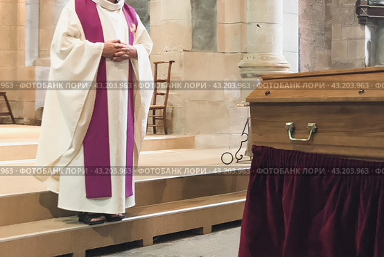 A priest in a church cassock conducts a funeral service in a French church. Стоковое фото, фотограф Irina Kuchugurina/Gaudy / Фотобанк Лори