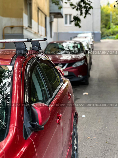 A red car is parked on the side of a street next to a white car. Стоковое фото, фотограф Ярославский Максим / Фотобанк Лори