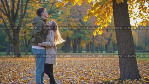 A Romantic Autumn Moment: A Couple Joyfully Embraces Amidst a Colorful Canopy of Falling Leaves and Warm Fall Colors in a Serene Park Setting. Стоковое AI-видео, аниматор Владимир Федоров / Фотобанк Лори