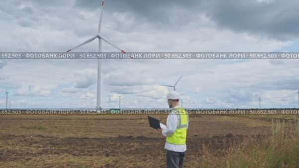 A safety expert inspects the wind turbine for any potential risks on a wet day before a thunderstorm. Стоковое видео, видеограф Strunov David / Фотобанк Лори