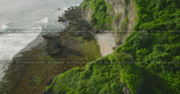 A scenic cliff above the ocean with lush greenery and sandy beach below (2024 год). Редакционное видео, видеограф Степанов Григорий / Фотобанк Лори
