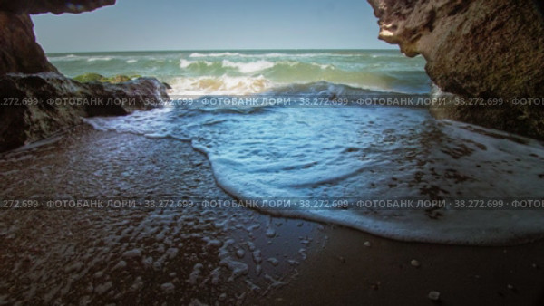 A secluded hideaway on the seashore, protected from all sides. The waves crash onto the sand, leaving a wet trail. A clear, sunny day. Long shot taken with a tripod. Стоковое видео, видеограф Даниил Хабаров / Фотобанк Лори