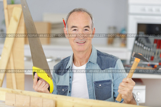 a senior man holding hacksaw. Стоковое фото, агентство Ingram Publishing / Фотобанк Лори