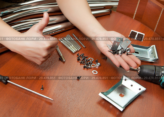 A set of mounting material for the Assembly of the dining table and a hand showing the thumb. Стоковое фото, фотограф Элина Гаревская / Фотобанк Лори