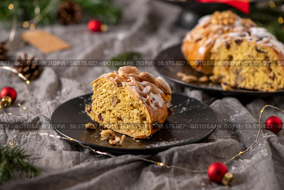 A slice of Bolo Rainha, adorned with almonds and powdered sugar, sits on a black plate. A whole cake is visible in the background, completing this festive still life. Стоковое фото, агентство Ingram Publishing / Фотобанк Лори
