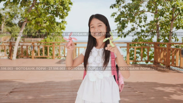 A small philippine schoolgirl shows spinning spinners. Tropical landscape. Summer. Childhood. Стоковое видео, видеограф Mikhail Davidovich / Фотобанк Лори