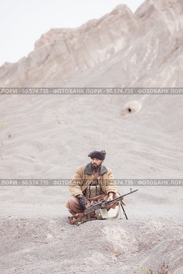 A Taliban soldier with a machine gun, In the desert mountain landscape. Стоковое фото, агентство Ingram Publishing / Фотобанк Лори