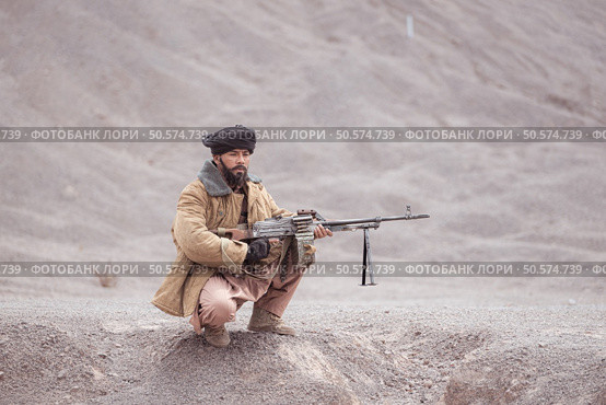 A Taliban soldier with a machine gun, In the desert mountain landscape. Стоковое фото, агентство Ingram Publishing / Фотобанк Лори