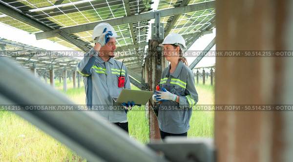 A team of electrical engineers is inspecting and maintaining solar panels at a solar panel site in the middle of a hundred acre field. Стоковое фото, агентство Ingram Publishing / Фотобанк Лори