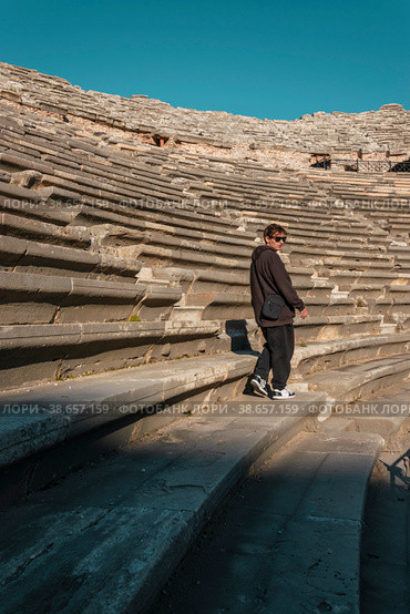 A teenager in a brown suit sits thoughtfully on the seat of an antique theater on a sunny day with dark glasses. Стоковое фото, фотограф Ярославский Максим / Фотобанк Лори