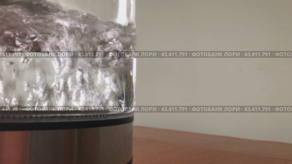 A transparent kettle of water is boiling on the table. Bubbles in close-up. Стоковое видео, видеограф Ярославский Максим / Фотобанк Лори