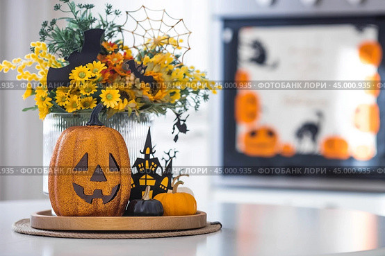 A vase of flowers, pumpkins and a scary castle with a witch on the background of a Scandi-style white kitchen interior. The concept of home and comfort. Autumn decor for Halloween. Стоковое фото, фотограф Photojuli / Фотобанк Лори