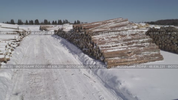 a view from a flying drone over a log warehouse at a woodworking factory in winter. Стоковое видео, видеограф Алексей Сергеев / Фотобанк Лори