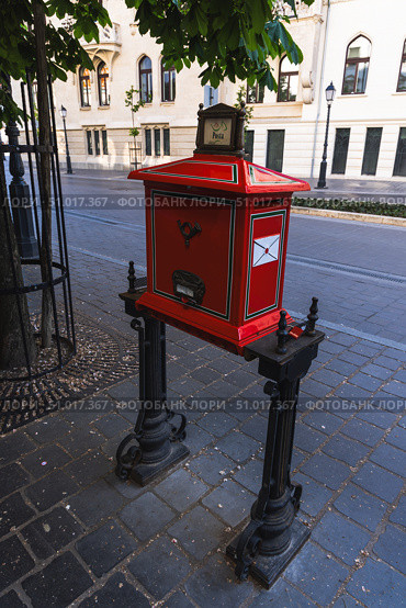 A vivid red vintage postbox stands on a cobblestone street. Редакционное фото, фотограф Виктор Ветошкин / Фотобанк Лори
