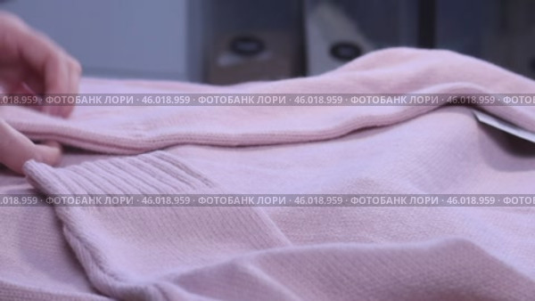 A woman is reviewing a knitted set. A knitted sweater and skirt. She is laying out the clothes on the table. Close-up. Стоковое видео, видеограф Vadzim Yakubovich / Фотобанк Лори