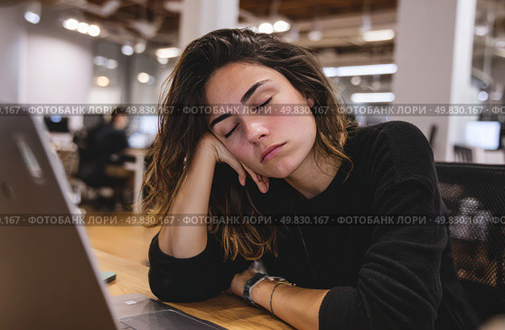 A woman is sleeping on a desk with a laptop on it. Стоковое AI-изображение, AI-художник Ярославский Максим / Фотобанк Лори