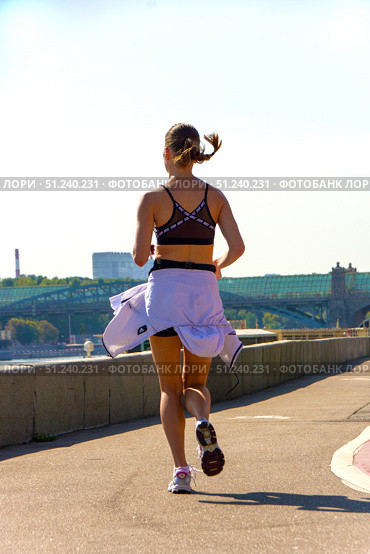 A woman runs on a sidewalk with a white jacket and a black tank top.  Russia. Moscow. 24.08.25. Редакционное фото, фотограф Ярославский Максим / Фотобанк Лори