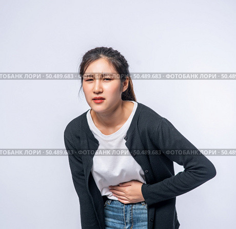 A woman standing with a stomach ache and presses her hand on her stomach. Стоковое фото, агентство Ingram Publishing / Фотобанк Лори