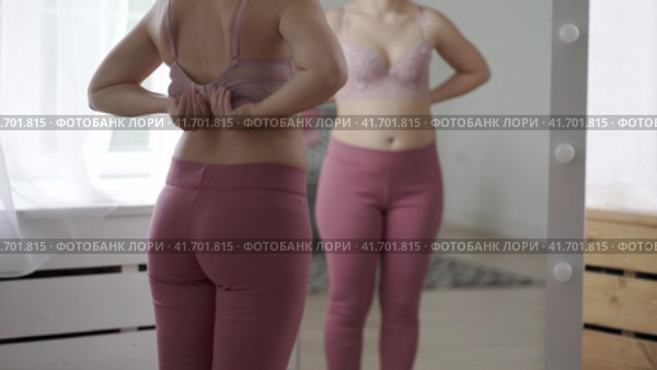 A woman tries on a bra in the fitting room, a bustier with a wide clasp is reflected in the mirror. Стоковое видео, видеограф Станислав Тарко / Фотобанк Лори