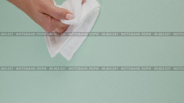 A woman's hand wipes water drops from a green rug with a white cloth. Стоковое видео, видеограф Катерина Белякина / Фотобанк Лори