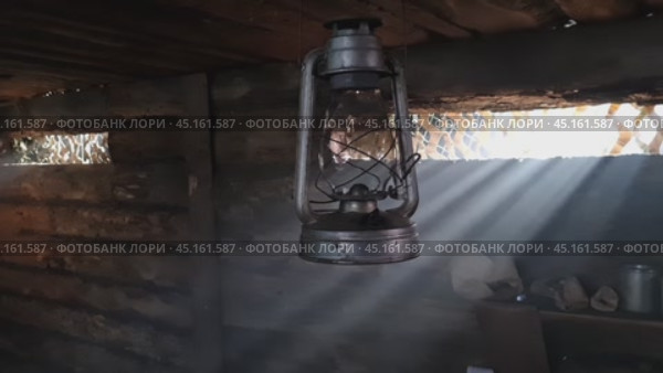 A wooden dugout in which a kerosene lamp burns. Light from the window penetrates into the room. Стоковое видео, видеограф Александр Кузовков / Фотобанк Лори